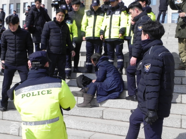 한 여성이 고함을 지르며 계단 앞으로 돌진하다가 경찰에 제지당하고 털석 앉아 있다. (사진=박효영 기자)