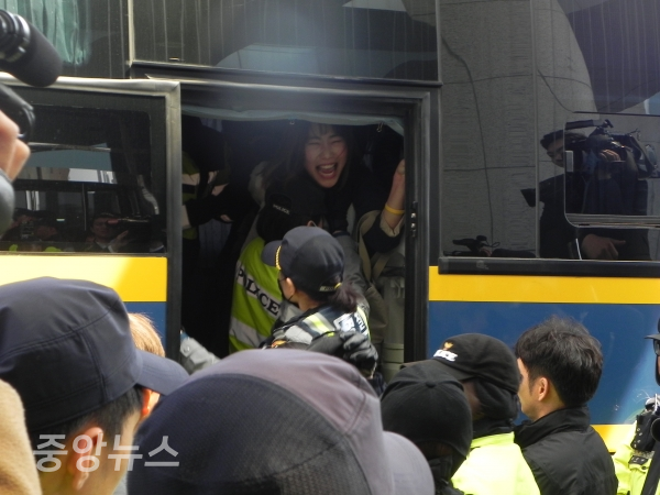 여성 경찰에 강제 연행된 한 회원이 버스에서 마지막 절규를 하고 있다. (사진=박효영 기자)