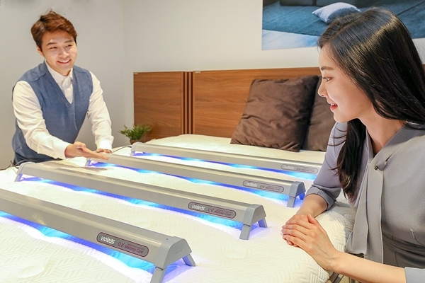 현대렌탈케어 직원과 모델이 고정형 LED 살균기를 사용해 살균 서비스를 제공하고 있다(사진=현대렌탈케어 제공)