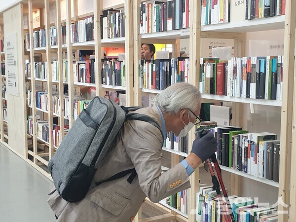 백발의 어르신이 서울국제도서전에 참가한 부스에사 책을 살펴보고 있다 (사진=신현지 기자) 