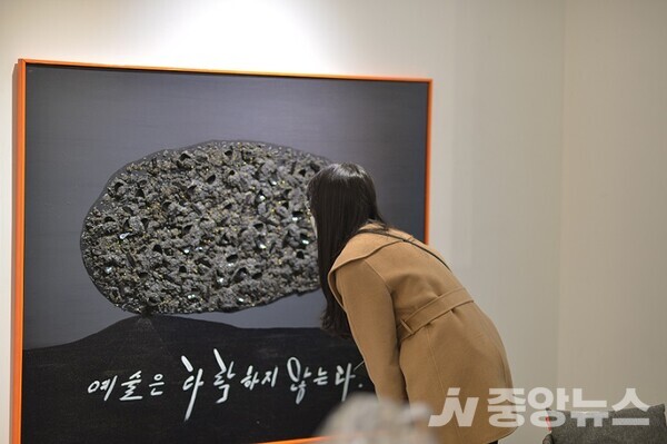 오성철 작가의 작품을 가까이에서 살펴보고 있는 관람객